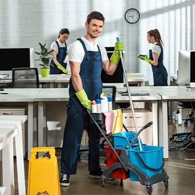 Reinigungskraft arbeitet mit professionellem Reinigungswagen in einem Gebäude