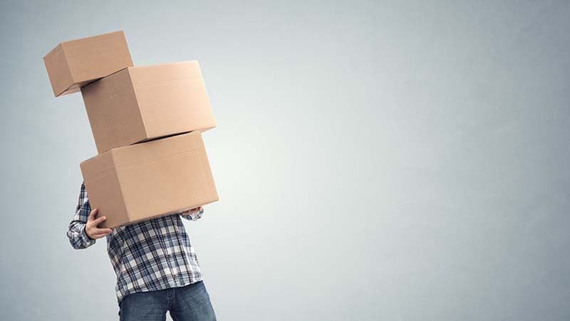 Mitarbeiter trägt mehrere Kartons als Symbol für Verpackungstipps und sicheren Versand für Unternehmen